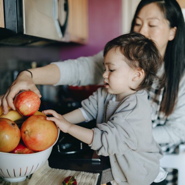 Mom and toddler choosing apple from a bowl