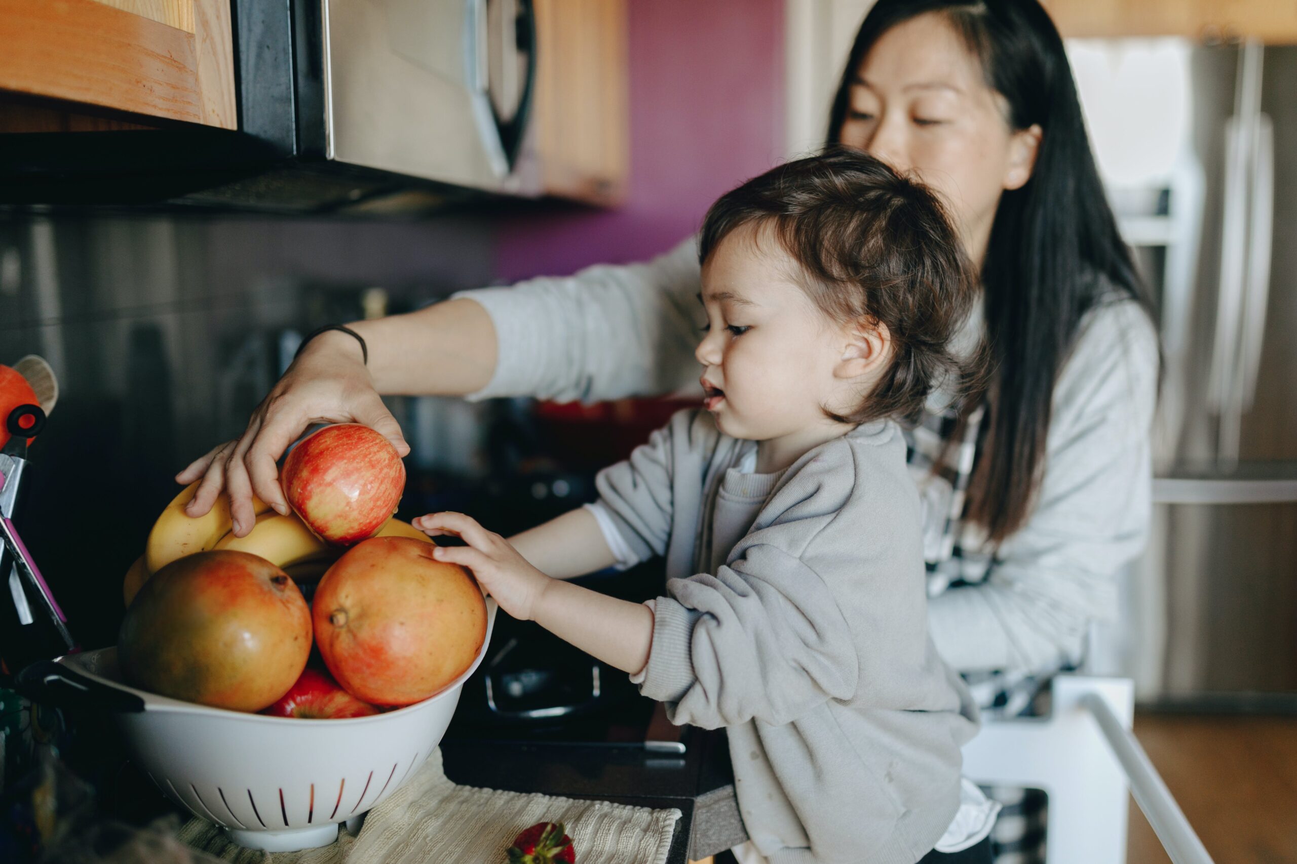 Mom and toddler choosing apple from a bowl